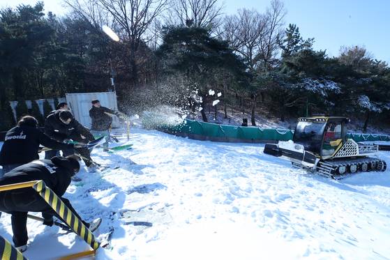Employees level piled artificial snow to create a sledding slope at the E-World theme park in Dalseo District, Daegu, on Jan. 2, as a cold wave continues. [NEWS1]
