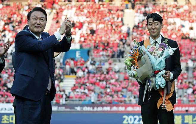 Son Heung-min, right, receives the Cheongnyong Medal, Korea’s highest sports honor, from then-President Yoon Suk Yeol at Seoul World Cup Stadium in western Seoul ahead of a friendly match between Korea and Brazil commemorating the 20th anniversary of the 2002 Korea-Japan World Cup on June 2, 2022. Son became the first Asian player to win the Premier League’s Golden Boot. [JOINT PRESS CORPS]