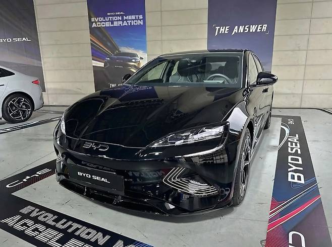 전시장 안에 전시된 매끄럽고 고급스러운 블랙 컬러의 byd 씰 전기차 외관