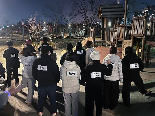 크리스마스이브인 지난해 12월 24일 서울 강서구 서울식물원 잔디밭에서 열린 '경찰과 도둑' 놀이에서 도둑 역할을 맡은 사람들이 등에 '도둑' 표시 종이를 붙이고 있다./연합뉴스