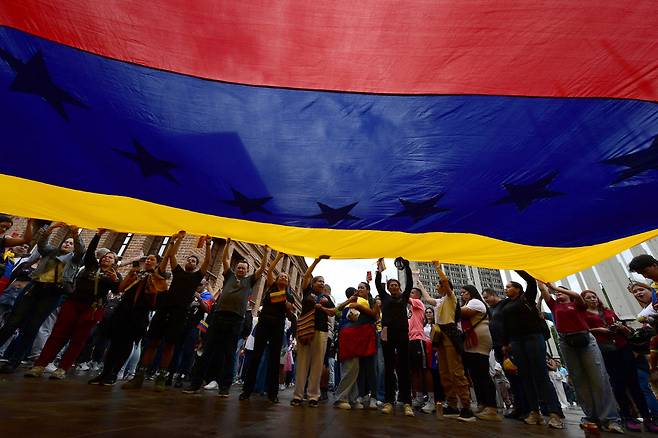 - People display a giant Venezuelan flag as they celebrate in Medellin, Colombia, on January 3, 2026, after US forces captured Venezuelan leader Nicolas Maduro. President Donald Trump said Saturday that US forces had captured Venezuela's leader Nicolas Maduro after bombing the capital Caracas and other cities in a dramatic climax to a months-long standoff between Trump and his Venezuelan arch-foe. AFP연합뉴스