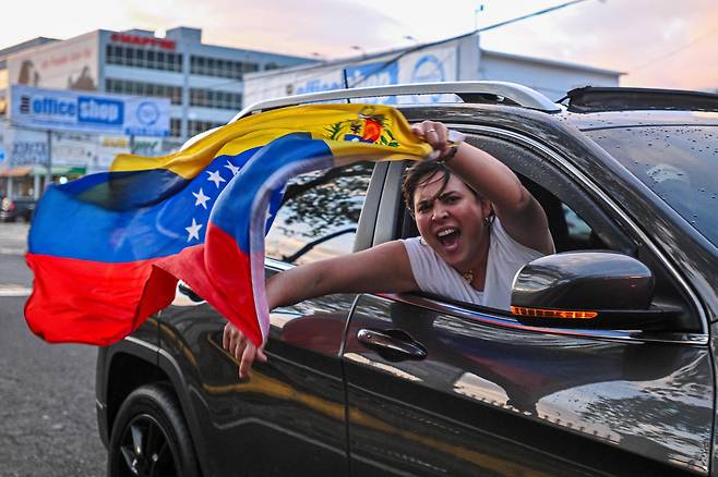 3일 푸에르토리코 산후안에서 미국의 마두로 체포 이후 한 사람이 베네수엘라 국기를 흔들고 있다. /연합뉴스