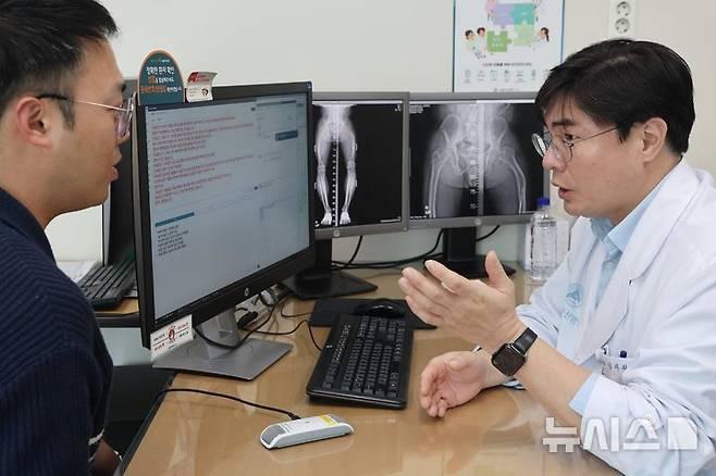 [서울=뉴시스] 김지완  서울아산병원 정형외과 교수가 인공지능(AI) 진료 음성인식 시스템을 활용해 환자를 진료하고 있다. 전용 마이크를 통해 입력된 의료진과 환자의 음성 데이터가 실시간 텍스트로 기록·요약되고, 주요 정보가 전자의무기록에 자동으로 저장된다. (사진= 서울아산병원 제공)