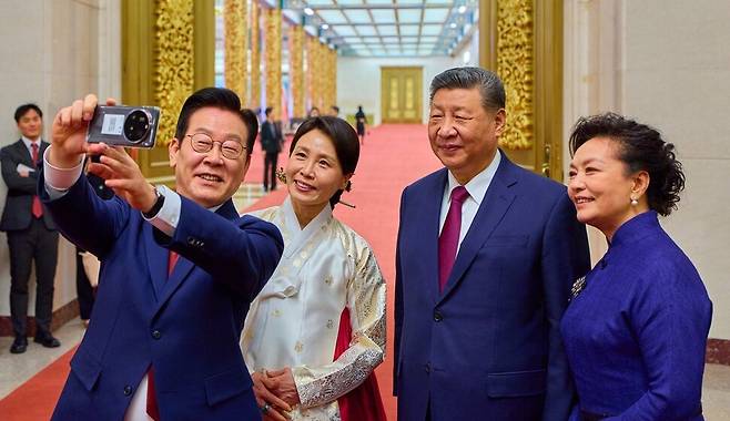 이재명 대통령 부부와 시진핑 국가주석 부부가 5일 중국 베이징 인민대회당에서 국빈만찬 후 샤오미폰으로 기념촬영을 하고 있다. 이 샤오미폰은 경주 정상회담 때 시 주석이 이 대통령에게 선물한 것이다.공동취재사진