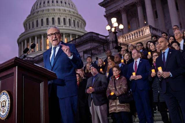미국 ‘1·6 의사당 폭동’ 사태가 벌어진 지 5년째 되는 날인 6일 척 슈머(맨 앞) 미 연방 상원 민주당 원내대표가 하킴 제프리스(두 번째 줄 맨 오른쪽) 하원 원내대표 등 민주당 연방 의원들과 함께 촛불을 들고 연방의회 의사당 앞에 모인 뒤 연설하고 있다. 이날 행사는 1·6 사태로 숨진 미국 의회 경찰관들을 추모하기 위해 열렸고 유족들도 초대됐다. 워싱턴=AP 연합뉴스