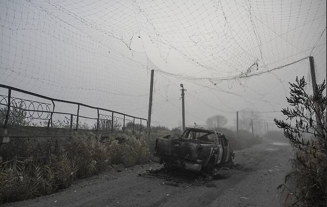 지난해 11월14일 우크라이나 자포리자의 최전선 마을인 훌리아일폴레. 드론 방어 그물로 덮힌 도로에 폭격맞은 트럭이 나뒹들고 있다. 로이터 연합뉴스