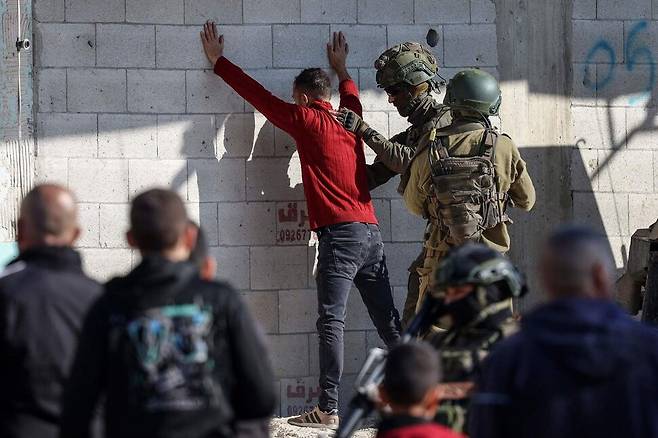 지난달 17일(현지시각) 요르단강 서안지구 툴카렘 인근 누르샴스 피난 캠프에서 이스라엘 군인이 한 팔레스타인 남성의 신체를 수색하고 있다. 이스라엘군은 팔레스타인 무장단체 색출 작업을 벌이며 주민들을 내쫓고 25개 건물을 파괴했다. AFP 연합뉴스