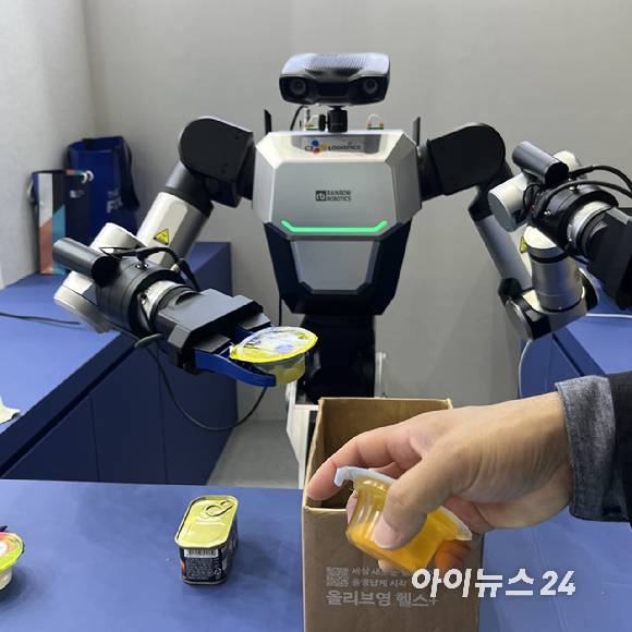 양팔 로봇이 CJ제일제당 쁘띠첼 과일 푸딩을 종이상자 안에 넣고 있다. [사진=권서아 기자]