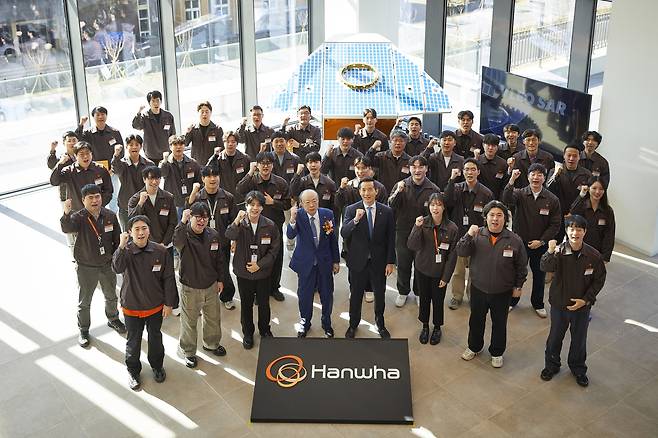 Hanwha Group Chairman Kim Seung-youn and Vice Chairman Kim Dong-kwan, both center in front row, pose for a photo with employees of Hanwha Systems at the Hanwha Space Center on Jeju Island on Jan. 8, in front of a full-scale model of the ultra-high-resolution synthetic-aperture radar satellite in very low Earth orbit. [HANWHA GROUP]