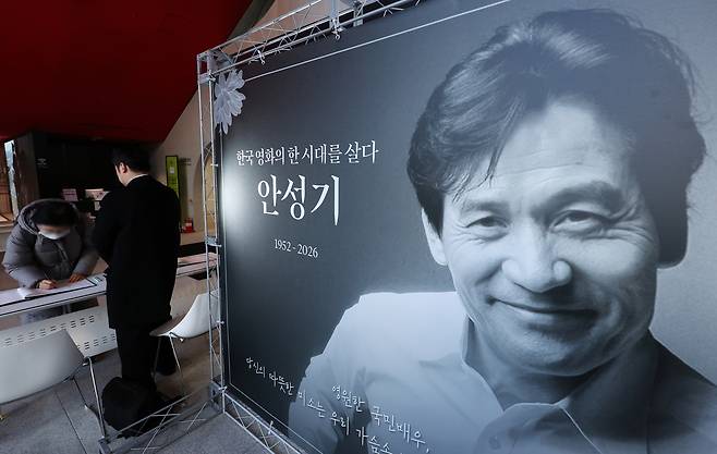 지난 6일 서울 중구 충무로 서울영화센터에 마련된 배우 고 안성기 추모공간을 찾은 시민이 방명록을 작성하고 있다. [연합]