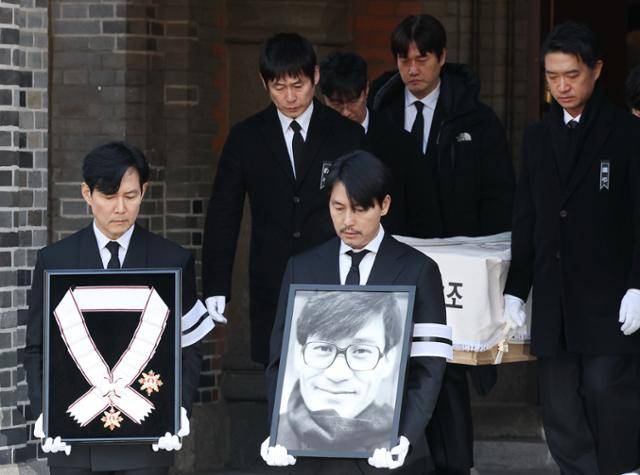 9일 서울 중구 명동성당에서 열린 배우 안성기의 장례 미사가 끝난 뒤 영결식을 위해 고인의 영정과 금관문화훈장을 든 배우 정우성, 이정재가 영결식장으로 향하고 있다. 연합뉴스