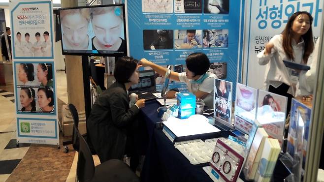 A tourist receives a cosmetic surgery consultation at an experience booth during Seomyeon Medical Street Festival held in Seomyeon, Busan, in 2017. [JOONGANG ILBO]