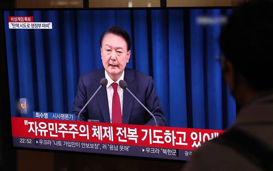Commuters watch news coverage at Seoul Station on the night of Dec. 3, 2024, after then-President Yoon Suk Yeol declared martial law in a national address. [NEWS1]