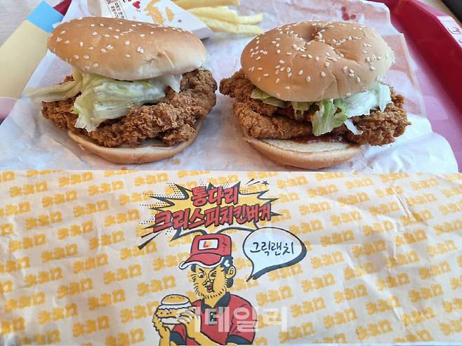 롯데리아 ‘통다리 크리스피치킨버거’. 좌측은 그릭랜치, 우측은 파이어핫 버전. 포장지에는 침착맨 캐릭터와 메뉴명이 인쇄돼 있다. (사진=한전진 기자)