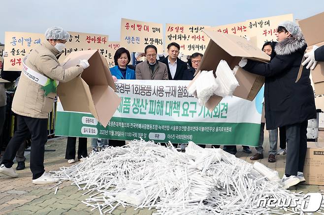 더불어민주당 을지로위원회와 종이빨대생존대책협의회 등 시민·사회 단체가 서울 여의도 국회 정문 앞에서 열린 '환경부 일회용품 사용 규제 철회로 인한 친환경제품 생산 피해 대책 요구 기자회견'에서 종이빨대 등 친환경제품을 바닥에 쏟는 퍼포먼스를 하고 있다. 2023.11.29/뉴스1 ⓒ News1 황기선 기자