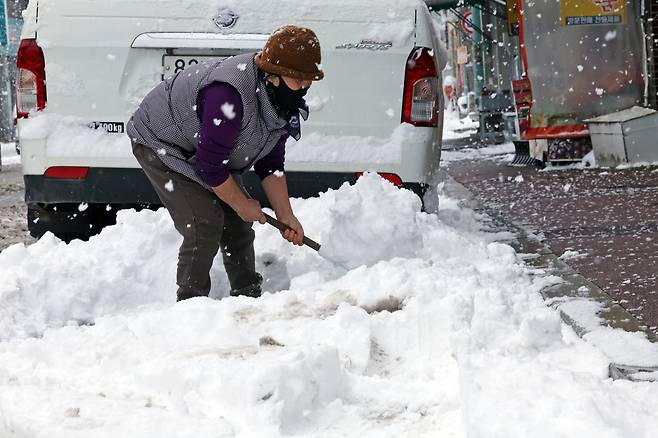 A resident shovels snow on a road in Muan, North Jeolla Province, on Sunday. (Yonhap)