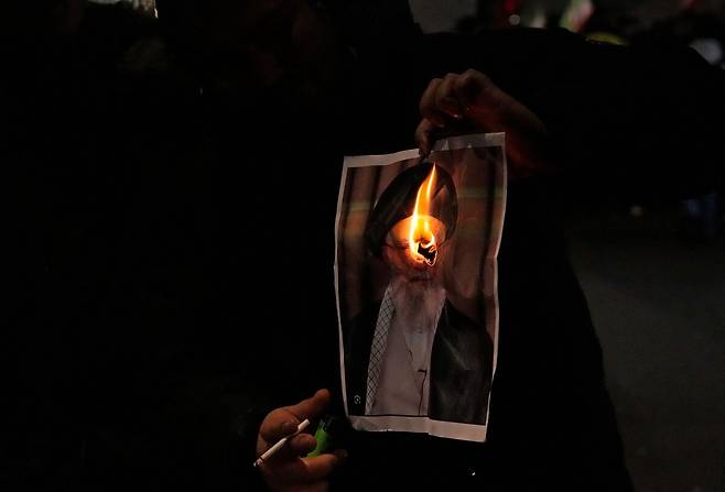 11일 영국 런던에서 열린 이란 연대 집회에서 한 시위대가 이란 최고지도자 아야톨라 하메네이의 사진을 불태우고 있다. 연합뉴스