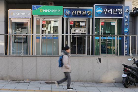 A pedestrian walks by ATMs in Seoul on Jan. 4. [YONHAP]