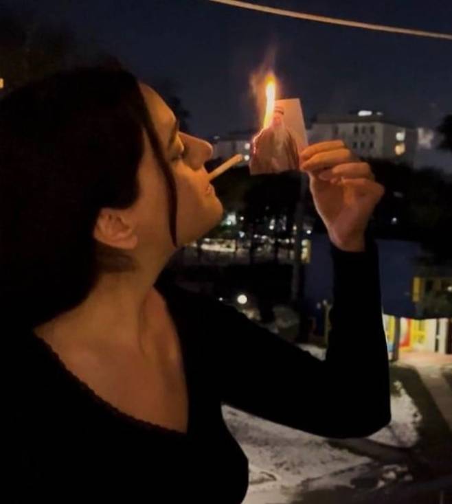 이란 최고지도자 아야톨라 알리 하메네이의 사진을 불 태우고 담뱃불로 쓰는 여성 . [X[