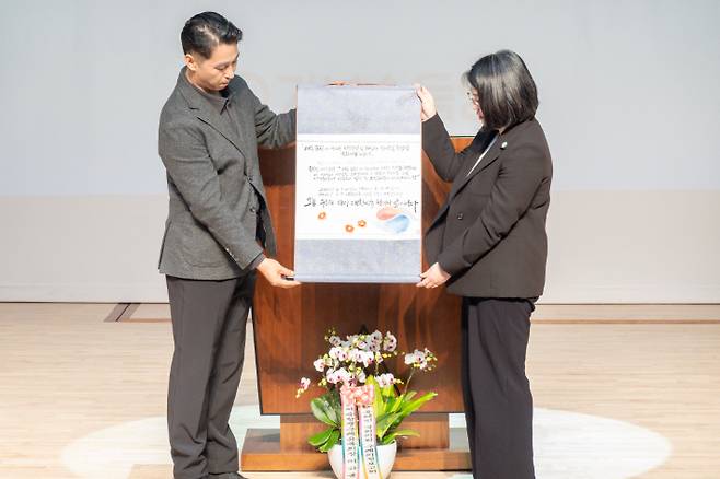 유족의 간절함을 담은 여순사건 특별법이 담긴 족자를 용혜인 의원에게 유족을 대표해 유족2세 이형용씨가 전달하고 있다. 용혜인 의원실 제공