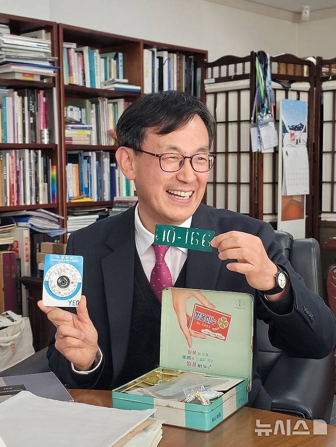 [서울=뉴시스]최희정 기자= 장상훈 국립민속박물관장이 7일 오후 서울 종로구 국립민속박물관에서 진행된 라운드 인터뷰에서 육군 논산훈련소 훈련병 시절 달았던 명찰, 시차 대조표 등 본인이 소장한 물품을 들어보이며 활짝 웃고 있다. 2026.01.12. dazzling@newsis.com