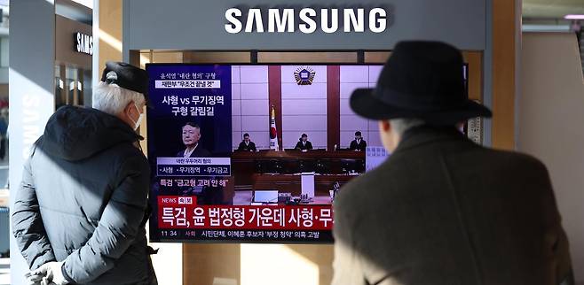 13일 서울 중구 서울역 대합실에서 이용객들이 윤석열 전 대통령의 내란 우두머리 혐의 재판 생중계를 TV로 시청하고 있다. 이날 윤 전 대통령 측은 ‘경고성 계엄’이었다는 기존 주장을 반복했다. 뉴시스