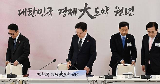 President Lee Jae Myung takes his seat at the public briefing on the 2026 economic growth strategy at the Blue House in central Seoul on Jan. 9. From left are Prime Minister Kim Min-seok, President Lee, Deputy Prime Minister and Finance Minister Koo Yun-cheol and Kim Ki-moon, chairman of the Korea Federation of SMEs. The slogan “The First Year of Korea’s Major Economic Leap Forward” is displayed in the background. [JOINT PRESS CORPS]