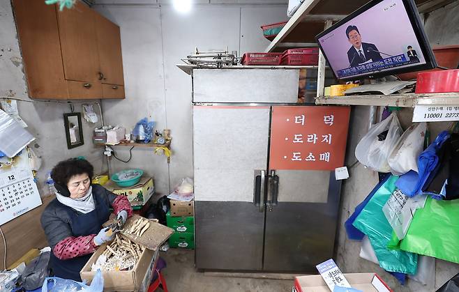 A merchant watches President Lee Jae Myung’s public briefing on the economic growth strategy on Jan. 9 at Gyeongdong Market in Dongdaemun District, eastern Seoul. [NEWS1]