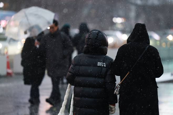People walk through Gwanghwamun Square in Jongno District, central Seoul, as it snows on Jan. 12. [YONHAP]