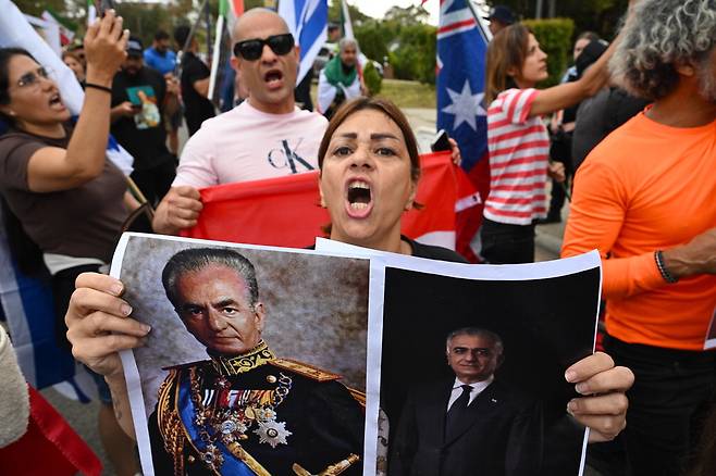 15일(현지시간) 호주 캔버라 주재 이란 대사관 인근에서 열린 이란 반정부 시위에서 한 참여자가 이란 팔레비 왕조 마지막 샤(국왕)인 무함마드 리자 팔레비(왼쪽)와 미국에 망명 중인 리자 팔레비 전 이란 왕세자의 사진을 들고 구호를 외치고 있다.  EPA연합뉴스