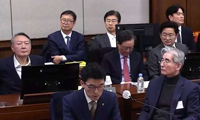 12·3 비상계엄 사태와 관련해 내란 우두머리 혐의로 구속기소된 윤석열 전 대통령(왼쪽)이 13일 1심 결심공판이 열리는 법정에 출석해 있다. 앞줄 오른쪽은 공범으로 재판에 넘겨진 김용현 전 국방부 장관. 서울중앙지법 제공