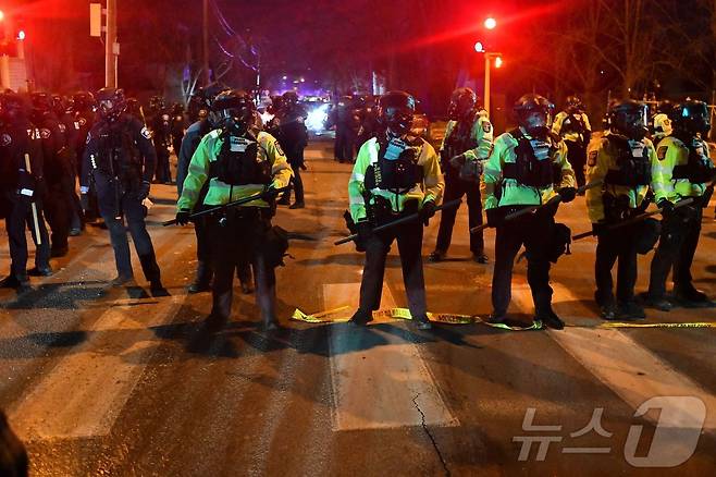 14일(현지시간) 미네소타주 미니애폴리스에서 시위대가 연방 법집행관과 충돌한 뒤 주 경찰관들이 도로에 줄을 지어 섰다. 이날 시 당국은 이민세관단속국(ICE) 요원이 베네수엘라 출신 남성을 총격했다고 밝혔다. 당국은 일주일 전 같은 도시에서 요원이 미국 여성에게 총격을 가해 사망하게 한 사건이 있었던 만큼 시민들에게 “침착함을 유지해 달라”고 당부했다.2026.1.14. ⓒ AFP=뉴스1 ⓒ News1 권영미 기자