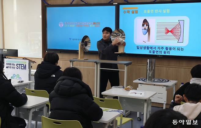 14일 서울 동작구 영등포중에 있는 ‘수학과학융합교육센터’의 수업에서 이성훈 개봉중 교사가 포물면 반사 실험기를 들고 학생들에게 포물선의 원리와 특성을 설명하고 있다. 학생들은 포물면 반사 실험기를 직접 보며 포물선이 손전등 등에 활용되는 것을 배웠다. 김재명 기자 base@donga.com