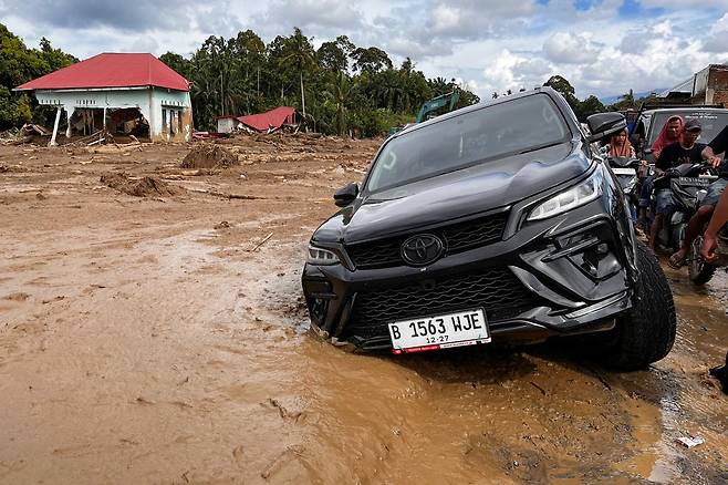 갑작스러운 홍수 피해를 입은 인도네시아 서수마트라 아감에서 한 차량이 진흙더미에 빠졌다. [AP]