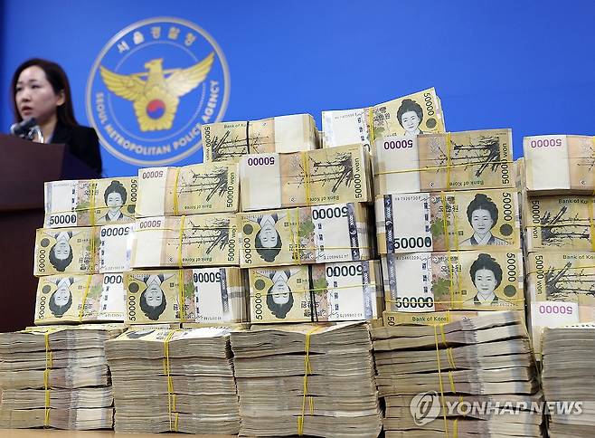 쌓여있는 범죄수익 현금다발  서울경찰청 광역수사단 금융범죄수사대는 2024년 3월 26일 허위 기업 상장 정보를 이용해 투자를 권유하는 수법으로 피해자 548명을 상대로 175억 원 상당을 편취한 비상장주식 판매 사기 범죄집단의 총책과 일당을 검거해 송치했다고 밝혔다. 사진은 서울경찰청 금융범죄수사대에 쌓여있는 41억여 원의 범죄수익 현금다발. 옆의 경찰은 김미애 금융범죄수사대 계장. 
[이지은 기자]