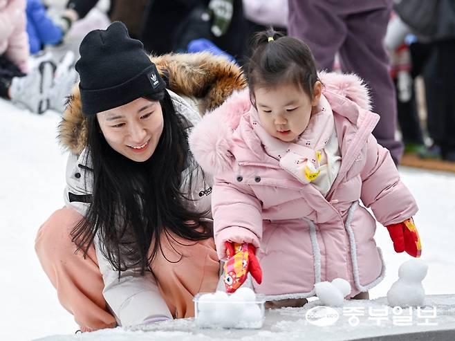 18일 오전 수원시 경기융합타운 내에 위치한 '경기도담뜰 겨울 눈밭 놀이터'를 찾은 어린이가 어머니와 함께 눈사람을 만들고 있다. 임채운기자