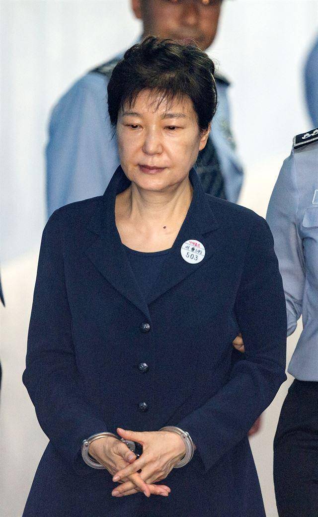 2017년 5월 23일 박근혜 전 대통령이 서울 서초구 서울중앙지법에서 열린 '국정 농단 사건' 첫 공판에 출석하기 위해 이동하고 있다. 옷깃에 부착된 '수인번호 503' 명찰과 양 손목에 채워진 수갑이 구속 상태로 재판에 넘겨진 그의 상황을 극명하게 보여 주고 있다. 류효진 기자