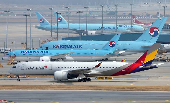 An Asiana Airlines plane passes in front of a Korean Air aircraft on a runway at Incheon International Airport on Feb. 13, 2024. [NEWS1]