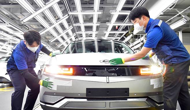 Workers inspect a vehicle on the production line for the Ioniq 5 EV at Hyundai Motor’s Ulsan plant. [HYUNDAI MOTOR]