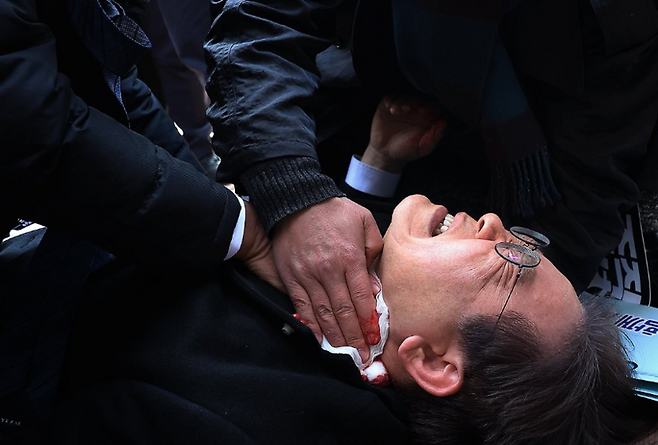 2024년 1월 2일 당시 이재명 더불어민주당 대표가 부산 가덕도 신공항 부지를 둘러본 후 기자들과 문답을 진행하던 중 왼쪽 목 부위에 습격을 당해 피를 흘린 채 쓰러진 순간 / 사진=연합뉴스