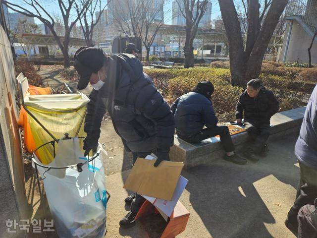 지난해 12월 30일 서울 종로구 종묘광장공원 장기·바둑장에서 조용근씨가 집게로 모은 쓰레기를 쓰레기봉투에 버리고 있다. 나광현 기자