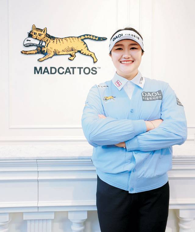 올해 자신의 첫 메이저대회 우승을 노리는 유해란이 지난 6일 자신의 새로운 의류 스폰서의 상징을 배경으로 포즈를 취하고 있다. 매드캐토스 제공