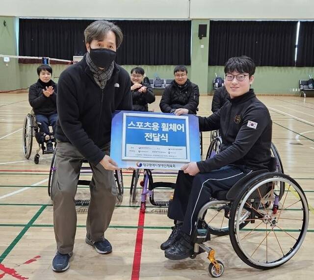 대구장애인체육회 홍준학 사무처장(왼쪽)이 탁구 선수들에게 스포츠용 휠체어를 전달하고 있다. 대구장애인체육회 제공