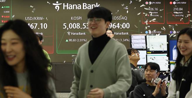 Dealers celebrate at Hana Bank’s dealing room in central Seoul after the KOSPI topped the 5,000 mark in early trading Thursday. (Yonhap)