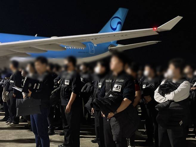 South Korean police officers wait at Phnom Penh Airport in Cambodia on Thursday near a Korean Air flight set to repatriate 73 South Koreans accused of scam crimes and sexual exploitation. (Yonhap)