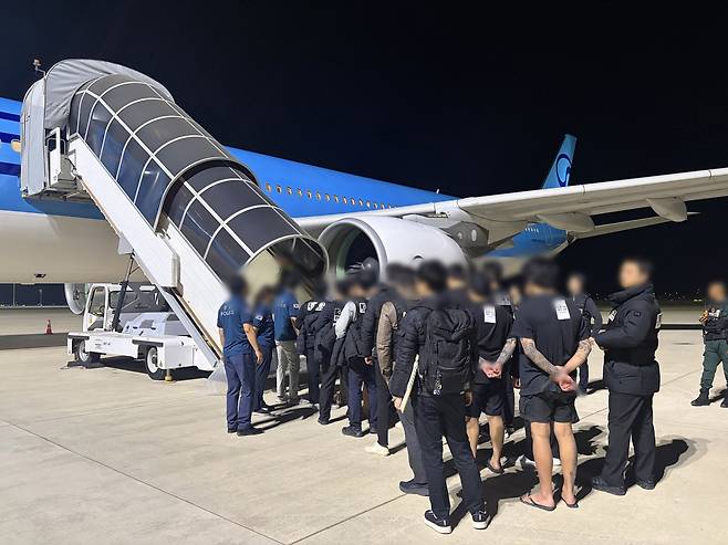Korean members of a criminal organization accused of carrying out scams and other crimes in Cambodia board a flight to be repatriated to South Korea on Thursday at Phnom Penh Airport. (Yonhap)