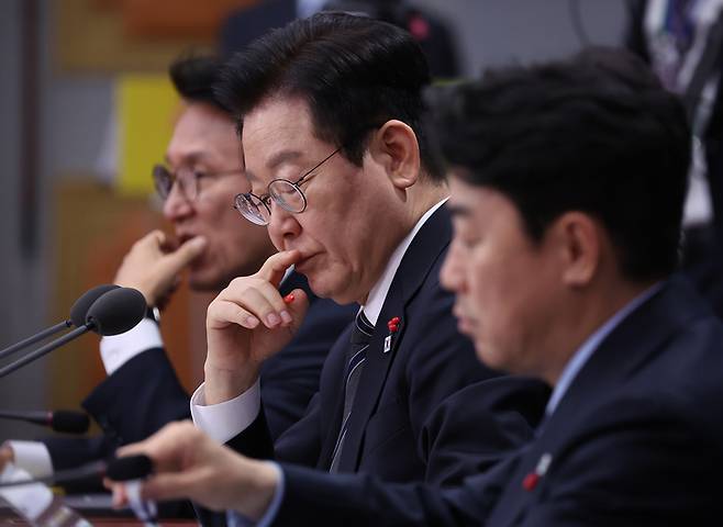 이재명 대통령이 19일 정부서울청사 별관에서 열린 금융위원회·공정거래위원회 업무보고에서 자료를 살펴보고 있다. 왼쪽부터 김민석 국무총리, 이재명 대통령, 강훈식 대통령 비서실장. 연합뉴스