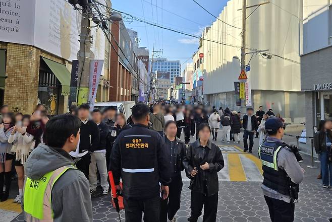 혼잡한 거리에서 경찰관들이 질서 유지를 위해 근무하고 있는 사진이다. 제목: 사람은 몰렸지만 사고는 없었다… 성수동 ‘인파사고 제로(ZERO)’ 이룬 비결?, 내용: 인파감지 지능형 CCTV 96대 집중배치 24시간 관제, 안전관리 전담요원 5명 배치, 주말 ‘성동형 보행안전거리’ 운영해 차량통제, 유튜브 ‘성수라이브’로 혼잡정보 제공