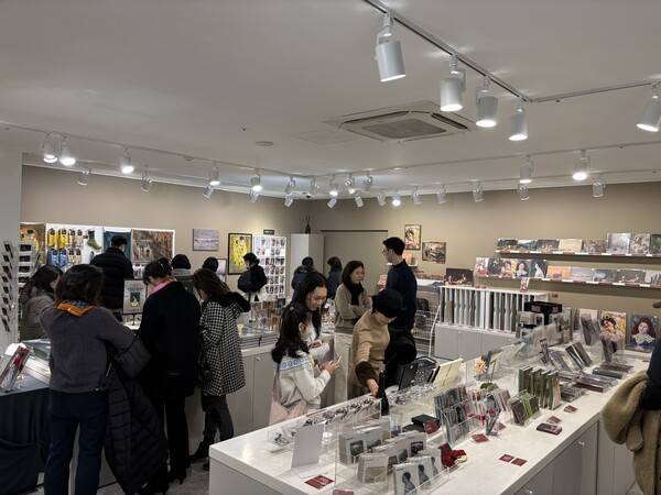 관람객들이 전시장 외부 굿즈샵에서 엽서, 마그넷, 화보 등 현재 진행 중인 전시 작품들이 담긴 굿즈를 구경하는 모습. [출처=이재아 기자]