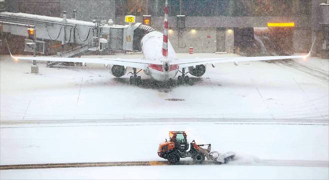 < 눈에 파묻힌 활주로 > 25일(현지시간) 미국 뉴욕 라과디아공항에서 제설차가 활주로에 쌓인 눈을 치우고 있다. 거대한 겨울 폭풍이 미국 전역을 덮치면서 미국 동부 공항에서는 항공편 취소가 잇따랐다.  AFP연합뉴스